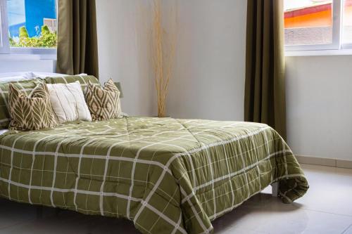 a bed with a green and white blanket on it at Maysi apartments in Willemstad