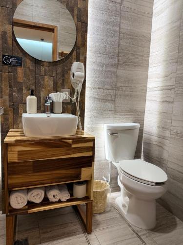 a bathroom with a sink and a toilet and a mirror at Casa Bocobá in Oaxaca City