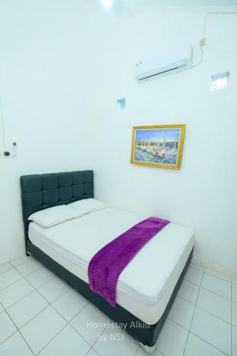 a bed in a room with a picture on the wall at Homestay Alkid in Timuran