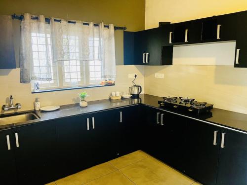 a kitchen with black cabinets and a sink and a window at Hidden Serene in Kalpetta
