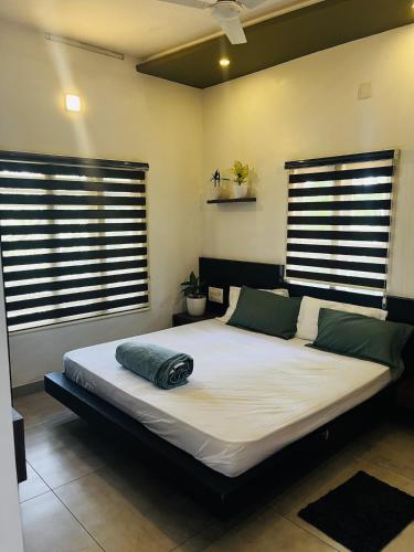 a large bed in a room with two windows at Hidden Serene in Kalpetta