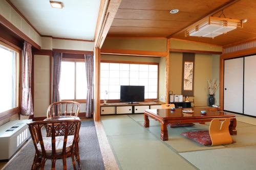 a living room with a table and a tv at Hotel Japan Shiga in Yamanouchi
