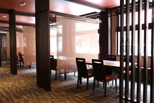 a dining room with a table and chairs and windows at Hotel Japan Shiga in Yamanouchi