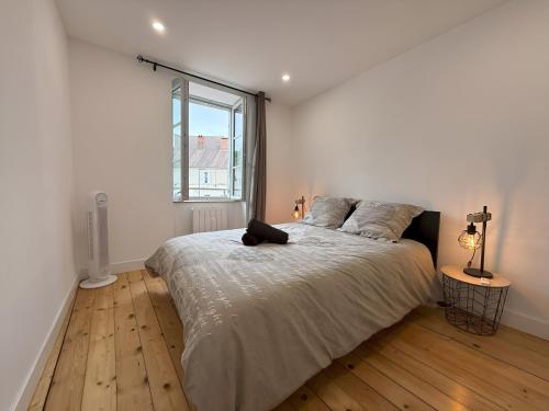a white bedroom with a large bed and a window at Maison au cœur d’Orgelet in Orgelet