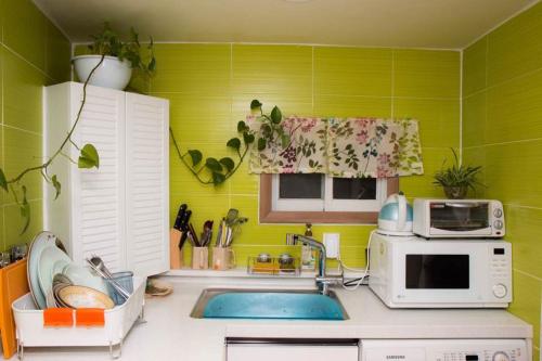 a green kitchen with a sink and a microwave at Lydia Craft Guesthouse in Seoul