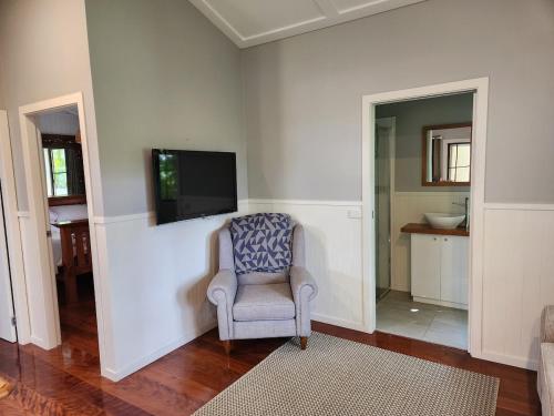 a living room with a chair and a flat screen tv at Hillside Hideaway - Your Base for the Region in Cawongla