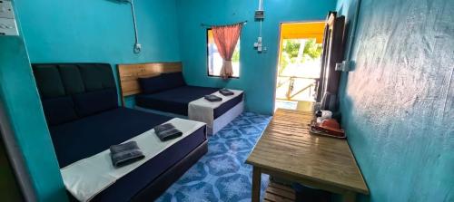 a room with two beds and a table and a couch at Rainbow Tioman Cottage in Kampong Juara