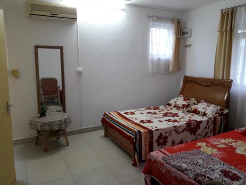 a small bedroom with two beds and a mirror at Bano Tourist Residence - 650 meters from Grand Bay Beach in Grand Baie