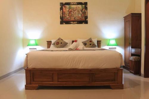 a bedroom with a large bed with two lamps at Reynold Artha Guest House in Nusa Lembongan