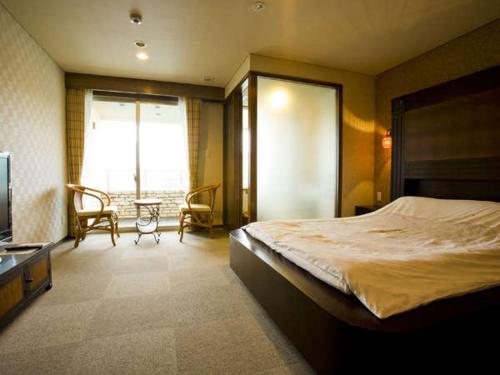 白浜町にあるホテル ルアンドン白浜のベッドルーム1室(ベッド1台、テーブル、椅子付)