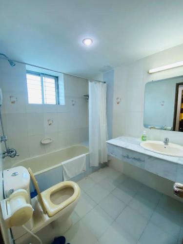 a bathroom with a toilet and a tub and a sink at Hotel Metro International in Sylhet