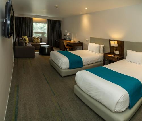 a hotel room with two beds and a couch at Hotel Casa Ciudad in Mexico City