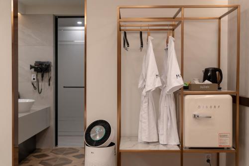 a bathroom with a rack with white shirts and a scale at 르벤토 호텔 in Jūrin-ri