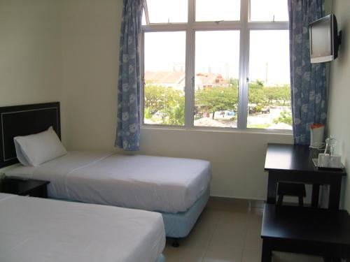 a hotel room with two beds and a window at Linkway Hotel in Nusajaya