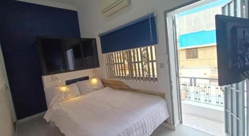 a bedroom with a white bed and a large window at Little Susie Double Room with Balcony in Phnom Penh