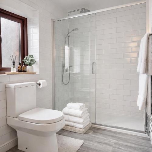a white bathroom with a shower and a toilet at Palmiro Cottage in Lapford