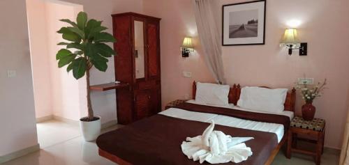 a hotel room with two beds and a potted plant at Hotel Cocobeach Kovalam in Kovalam