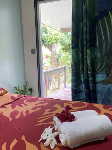 ein Bett mit einem Handtuch und Blumen darauf in der Unterkunft Fare anuhe in Bora Bora