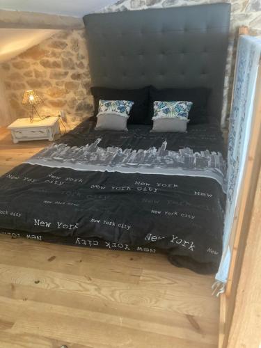 a bed with a black comforter and two pillows at Le Mafaté - Vallée de l'Eyrieux in Saint Maurice en Chalencon