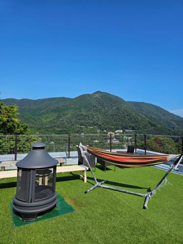 a hammock and a boat on the grass with a mountain at Hakone Guest House gaku. in Hakone
