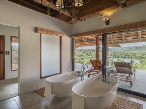 a bathroom with two sinks and a large window at Lions Valley Lodge in Nambiti Game Reserve