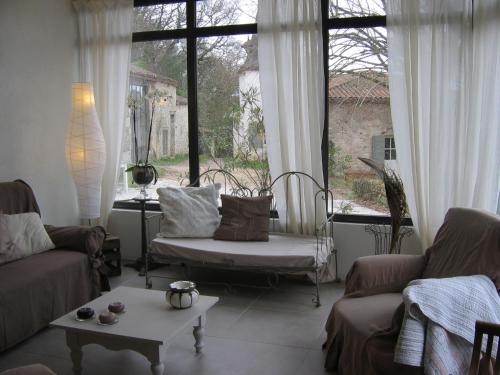 - un salon avec un canapé, une table et des fenêtres dans l'établissement Gîtes Le Relais de Roquefereau, à Penne-dʼAgenais
