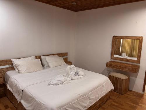 a bedroom with a bed with white sheets and a mirror at Villa Lumbung sari in Badung