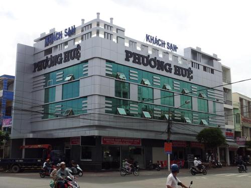 ein Gebäude mit Leuten, die vor ihm Motorrad fahren in der Unterkunft Phuong Hue Hotel in Soc Trang