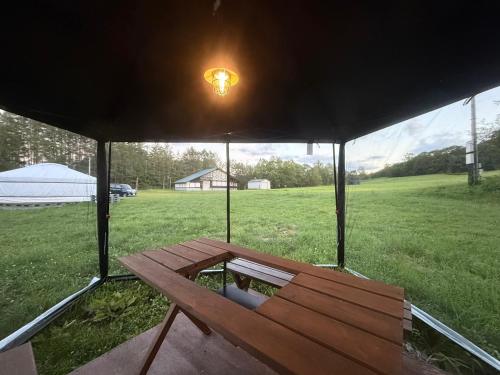 a picnic table under a tent in a field at モンゴルゲルグランピング Frontier Village in Tōma