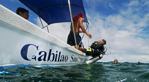 a man on a sail boat in the ocean at Cabilao Sanctuary Beach & Dive Resort in Loon
