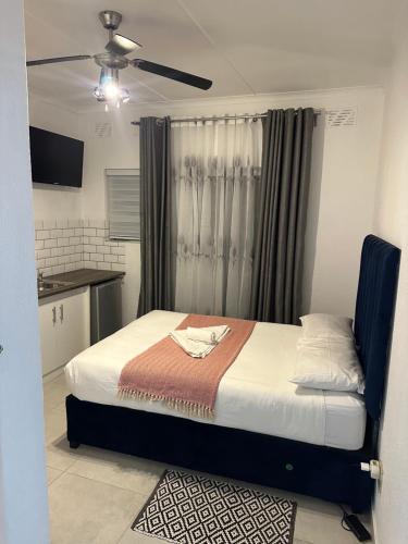 a bedroom with a bed and a ceiling fan at Bell rose oaks guest house in Blomtuin