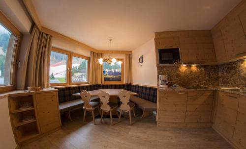 une cuisine avec une table et des chaises. dans l'établissement Apartments Edera, à Selva di Val Gardena