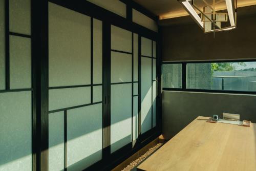 a room with a wooden table and windows at Achroma de Hanok in Seogwipo