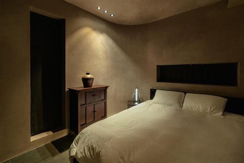 a bedroom with a white bed and a wooden dresser at Achroma de Hanok in Seogwipo