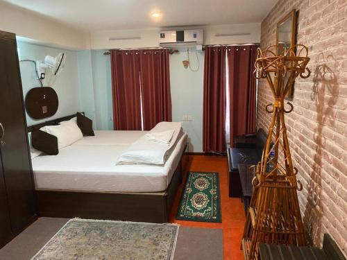 a small bedroom with a bed and a brick wall at Hotel Malla Inn in Bhaktapur