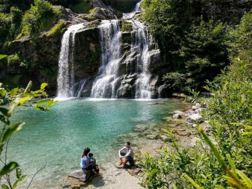 three people sitting on rocks in front of a waterfall at Casa Piumogna in Faido