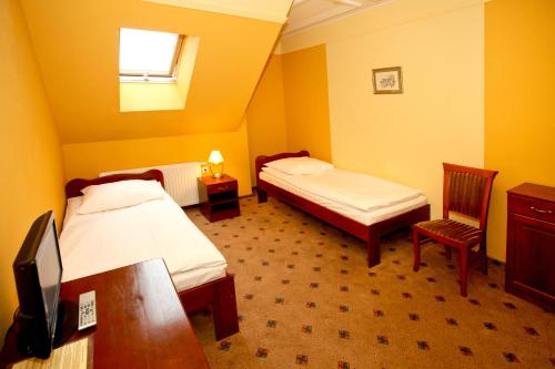 a room with two beds and a desk and a tv at Zajazd Partynia in Partynia