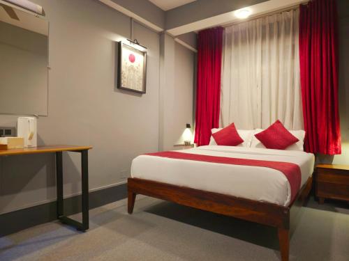 a bedroom with a bed with red curtains and a desk at Mayuri Lodge in Kalimpong
