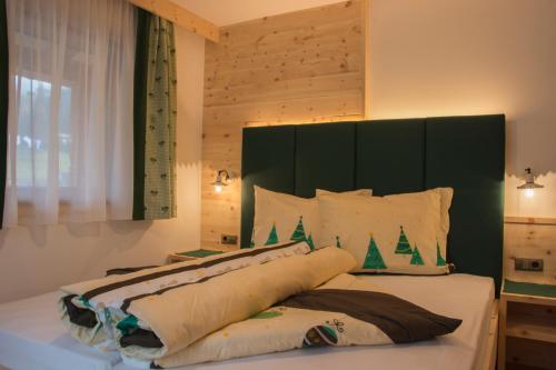 セルヴァ・ディ・ヴァル・ガルデーナにあるApartments Ederaのベッドルーム1室(緑のヘッドボード付きの大型ベッド1台付)