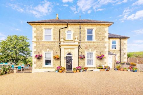 a stone house with flowers in the front yard at Clevelands Country House in Wroxall