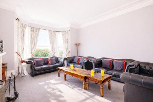 a living room with leather couches and a coffee table at Clevelands Country House in Wroxall