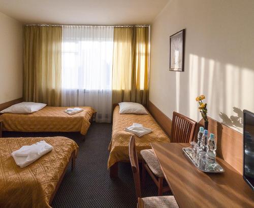 ルブリンにあるホテルズルブリンのベッド3台とテーブルが備わるホテルルームです。
