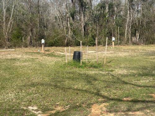 a field with a black object in the grass at RV Sites at Off the Road Oasis in Lufkin