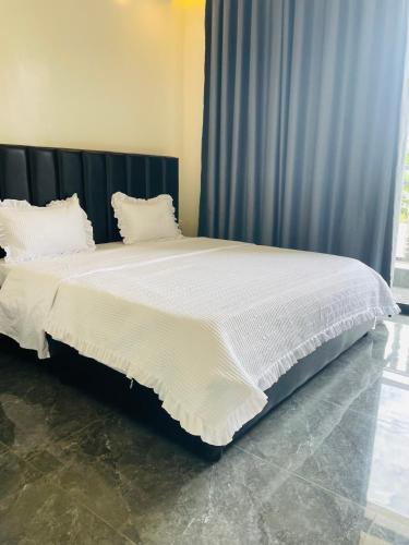 a large bed with white sheets and pillows at KiGALI COMFORT AND CLASSIC STAY APARTMENT in Kigali