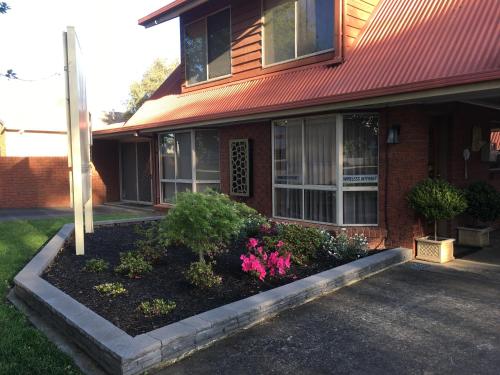 a house with a flower bed in front of it at AAt 28 Goldsmith Motel in Hamilton