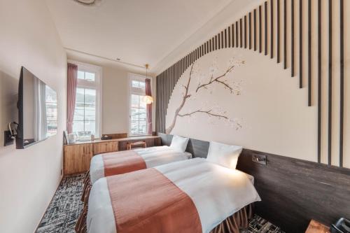 a bedroom with two beds and a tree painting on the wall at T9 Hakodate in Hakodate