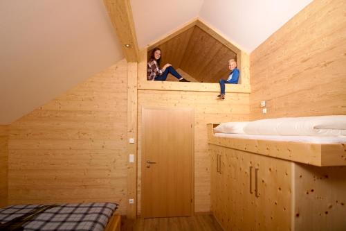 zwei Personen sitzen auf einem Holzhaus in der Unterkunft Bio Chalet "Sonne" in Weisspriach