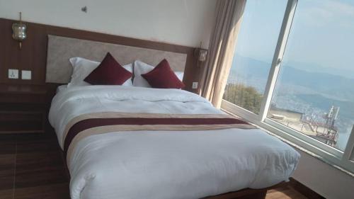 una camera da letto con un letto grande con una grande finestra di Dawn view lodge a Pokhara