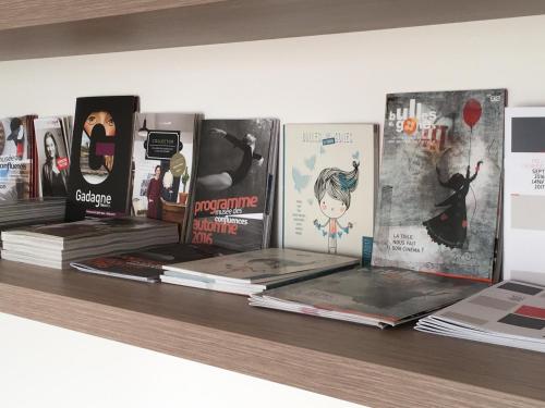 a shelf with books and magazines on it at Mon Appart A GERLAND II in Lyon