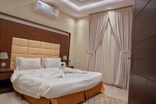 a bedroom with a large bed with white sheets at شقق سما الرفاع للشقق المخدومة in Al Kharj